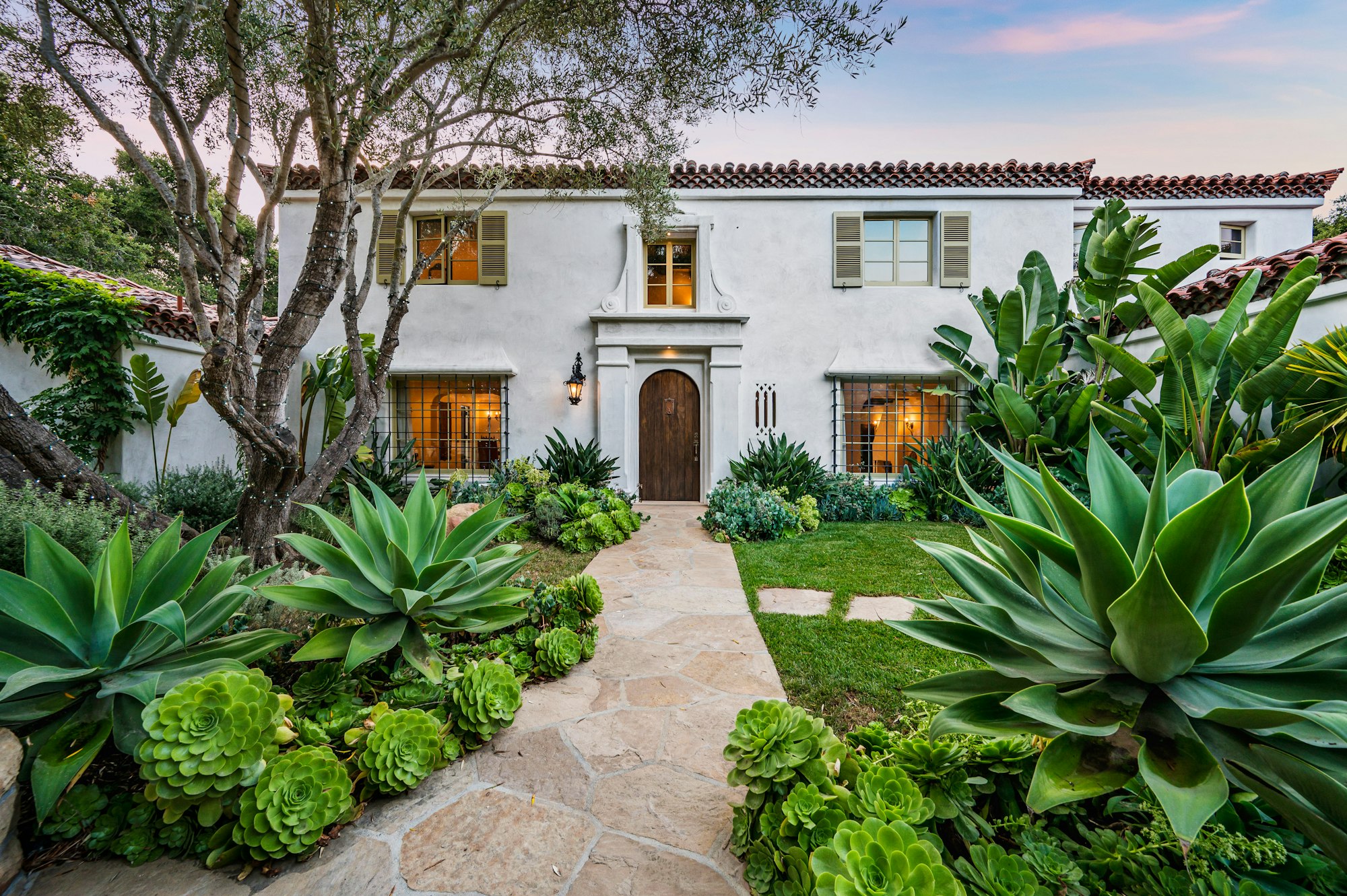 a home with a garden and landscaping on either side of it